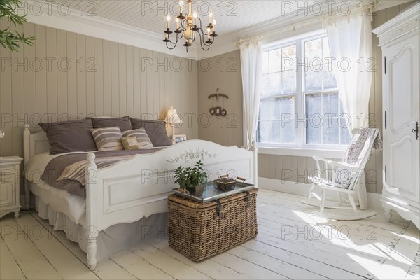 King size bed with light brown and beige striped bedspread, white painted wooden headboard and