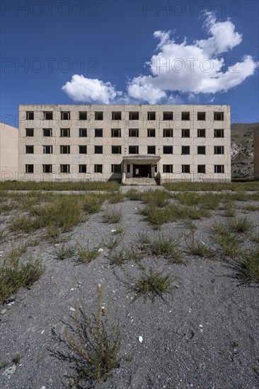 Abandoned destroyed residential building, old Soviet block of flats in the ghost town, Engilchek,