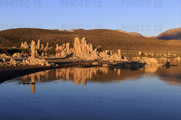 Warm sunset light on tufa towers at Mono Lake with calm water reflection, Mono Lake, North America,