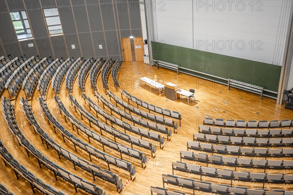 View from above into an empty lecture theatre with rows of seats and lectern, interior photo,