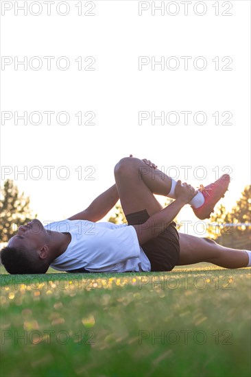 Football player with leg pain on the field. Football player lying on the grass rubbing his leg.