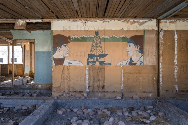 Destroyed abandoned classroom of the old school, wall painting with Soviet miners, ghost town,