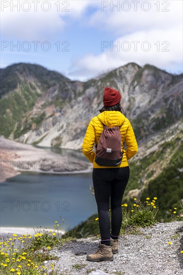Young woman in yellow jacket standing in front of a volcano, Chaiten Volcano, Carretara Austral,