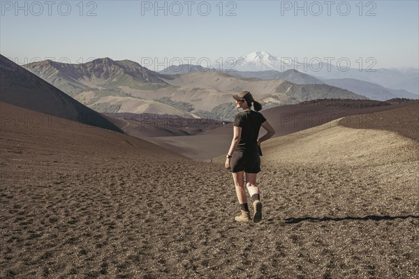 Young woman walking through lava fields, Crater Navidad, Lonquimay volcano, Malalcahuello National