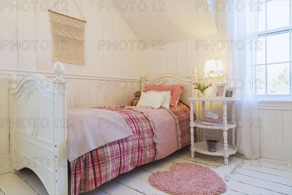 Single bed with red, pink and grey tartan bedspread, white painted antique style wooden headboard