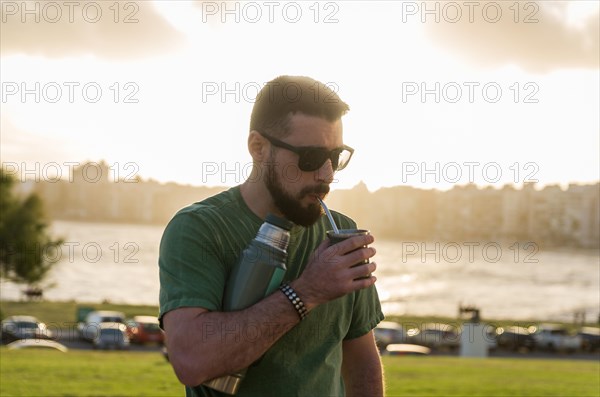 Man drinking chimarrao, mate tea tea (an infusion of yerba mate tea tea with hot water) at sunset