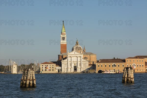 Canal lane markers in Venetian lagoon and 16th century Benedictine church of San Giorgio Maggiore