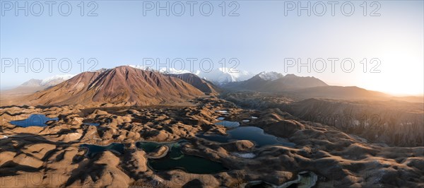 Atmospheric aerial view, high mountain landscape with glacier moraines and mountain lakes, behind