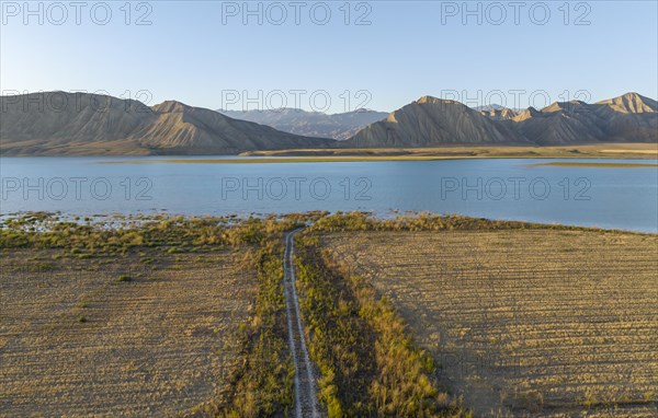 Dirt road leads between fields to the lake, Toktogul reservoir, aerial view, Toktogul, Kyrgyzstan,
