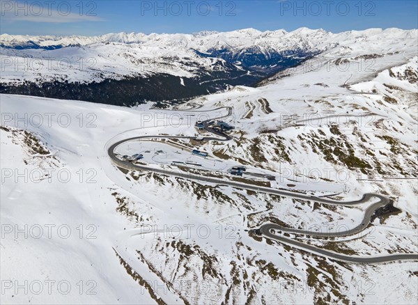 Mountain road winds through a wintry landscape in daylight, serpentine road near El Pas de la Casa,