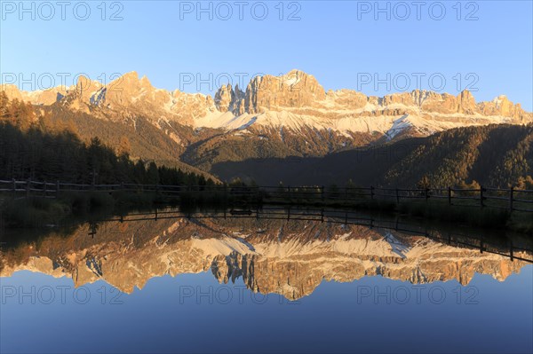 Sunrise behind the mountains with bright red colours reflected in the clear water of the lake,
