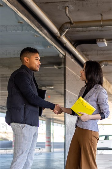 Woman in formal suit shaking hands with casual man outdoors. Business woman shaking hands with guy