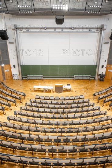 View from above into an empty lecture theatre with rows of seats and lectern, interior photo,