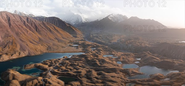 Atmospheric aerial view, high mountain landscape with glacier moraines and mountain lakes, behind