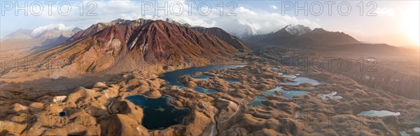 Atmospheric aerial view, high mountain landscape with glacier moraines and mountain lakes, behind