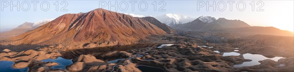 Atmospheric aerial view, high mountain landscape with glacier moraines and mountain lakes, behind