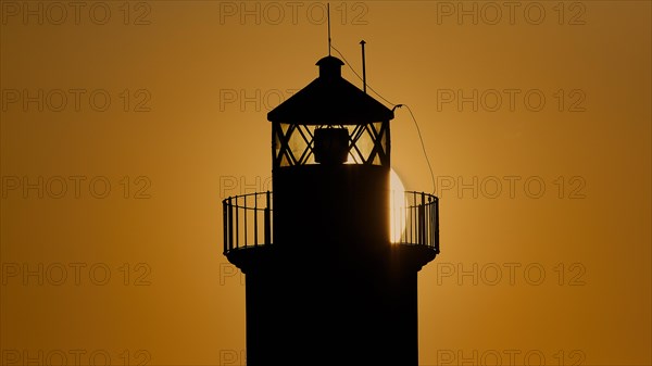 A lighthouse in silhouette with a dazzling sunrise in the background, sunrise, dawn, Fort of Saint