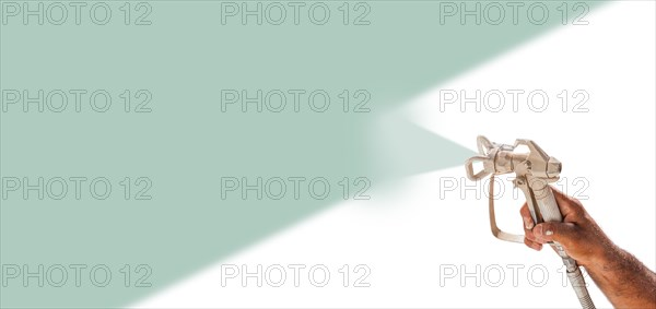 Professional spray painter holding spray gun spraying teal over white surface