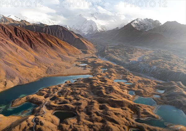 Atmospheric aerial view, high mountain landscape with glacier moraines and mountain lakes, behind