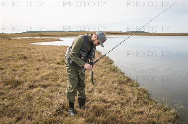 Sport fisherman fishing in lake on cloudy day, Cambara do sul, Rio Grande do sul, Brazil, South