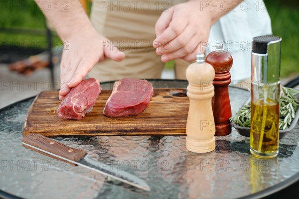 Unrecognizable man rubbing olive oil with hand over raw beef strip steak