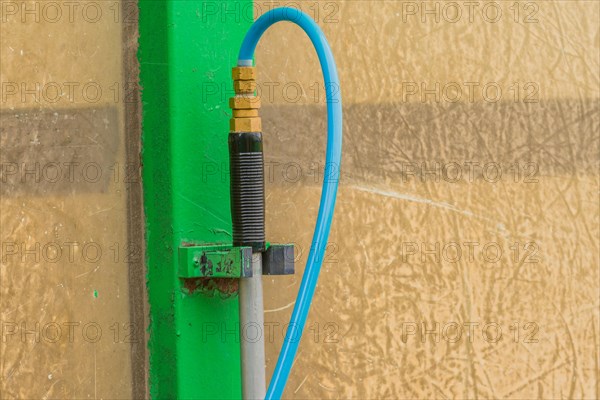 Closeup of handle of car wash brush with attached blue water hose in South Korea