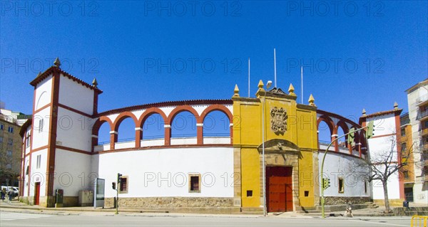 Bright historic building with red accents and coat of arms under a clear blue sky in an urban