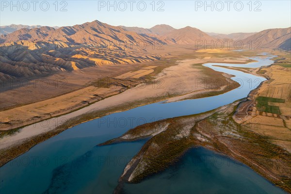 Naryn River between mountains and fields, at Toktogul Reservoir at sunset, aerial view, Kyrgyzstan,