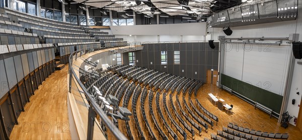View from the gallery into an empty lecture theatre with rows of seats and lectern, interior photo,