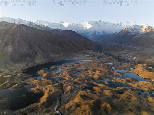 Atmospheric aerial view, high mountain landscape with glacier moraines and mountain lakes, behind
