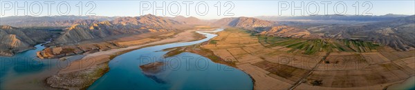 Panorama, Naryn river between mountains and fields, at Toktogul reservoir at sunset, aerial view,