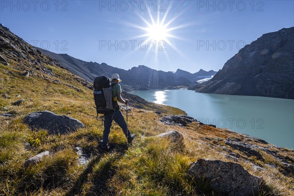 Mountaineers at the turquoise Ala Kul mountain lake in the morning light, Sun Star, Tien Shan