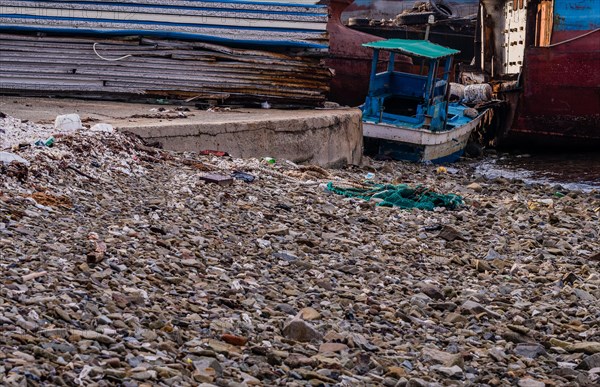 Old rusty abandoned ships sitting on the shore amid trash and debris at a marine junkyard in South
