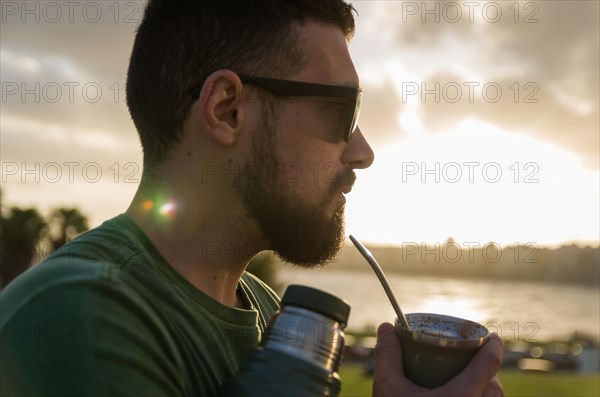 Man drinking chimarrao, mate tea tea (an infusion of yerba mate tea tea with hot water) at sunset