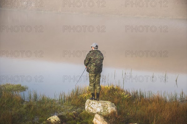 Sport fisherman fishing in lake on cloudy day, Cambara do sul, Rio Grande do sul, Brazil, South