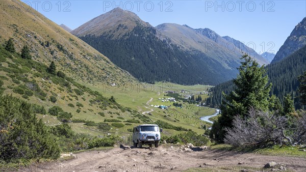 UAZ Buchanka, Russian off-road vehicle on 4x4 track, green mountain valley with village Altyn