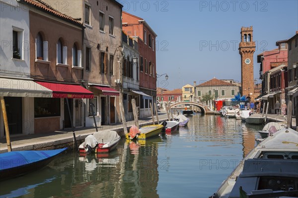 Moored boats on canal with colourful residential buildings, houses, shops and clock tower in San