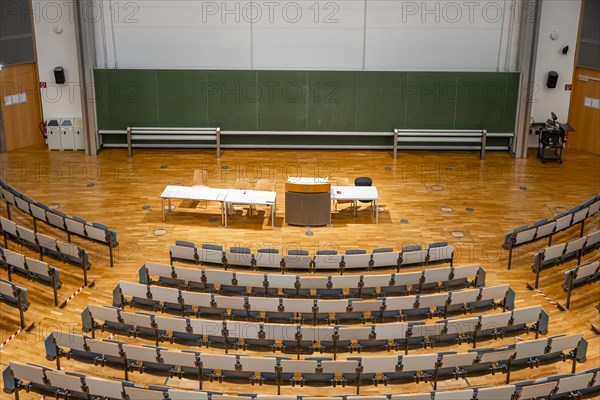 View from above into an empty lecture theatre with rows of seats and lectern, interior photo,