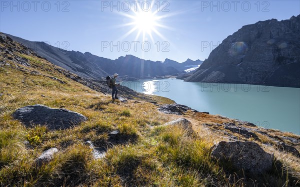 Mountaineers at the turquoise Ala Kul mountain lake in the morning light, Sun Star, Tien Shan