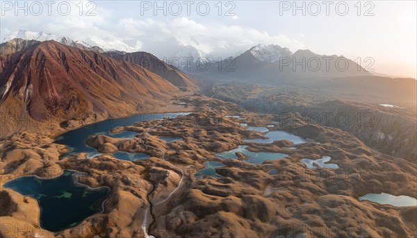 Atmospheric aerial view, high mountain landscape with glacier moraines and mountain lakes, behind