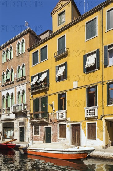 Narrow canal with moored boats and Renaissance architectural style residential palace buildings,