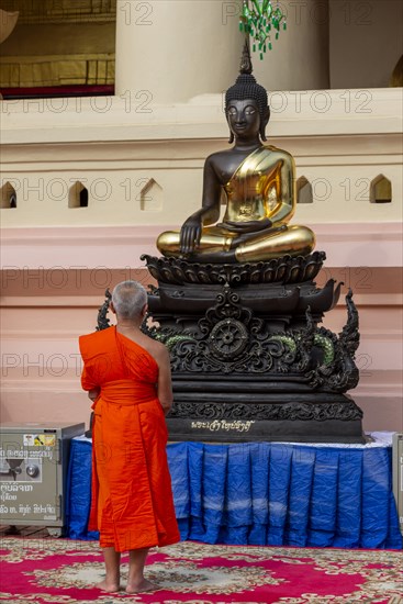 Monk in front of a Buddha statue, Bhumispara-mudra, Buddha Gautama at the moment of enlightenment,