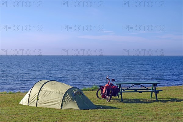 Tent and bike in a meadow with a view of the open sea, Cycling holidays, Outdoor, Husavik, Iceland,