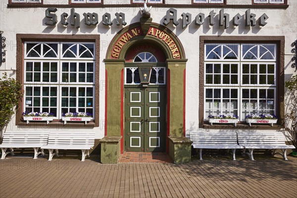 Entrance door of the Swan pharmacy with windows, flower boxes and benches in the city centre of