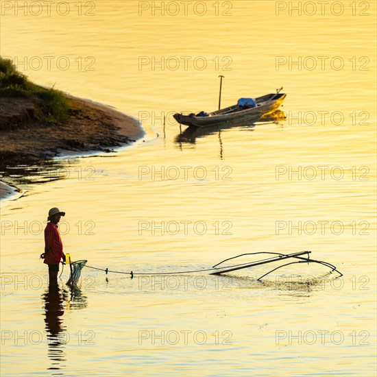 Fisherman with a sinking net at sunset on the Mekong, Luang Prabang, Laos, Asia