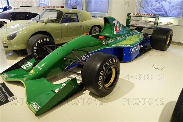 JORDAN 191 F1 MICHAEL SCHUHMACHER, A green Jordan Formula 1 racing car with sponsors in a showroom,