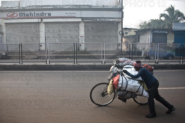 Man, carrying on bike, street, coal, selling to urban dwellers, restaurants, shops, Dhanbad, Bihar,