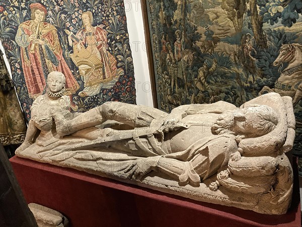 Exhibit historical tomb slab of knight nobleman in the background old historical tapestry