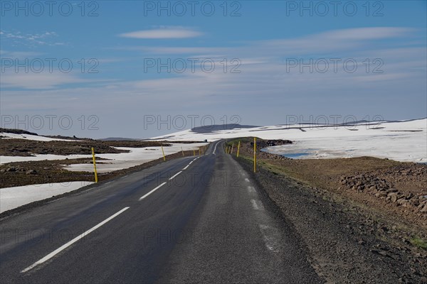 Road leads through barren mountain landscape with snow and ice, Seydisfjoerdur, Fjaroarheioi,