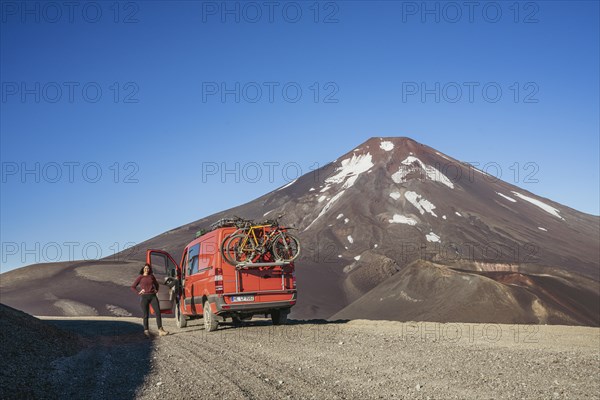 Young woman and her campervan in front of the Lonquimay volcano, Lonquimay volcano, Malalcahuello